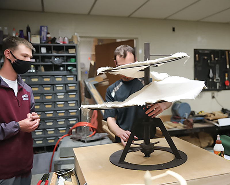 Joseph Watson fits the freshly cut canvas helicopter “blades” to the model. Photo courtesy of the McMurry Advancement Office.